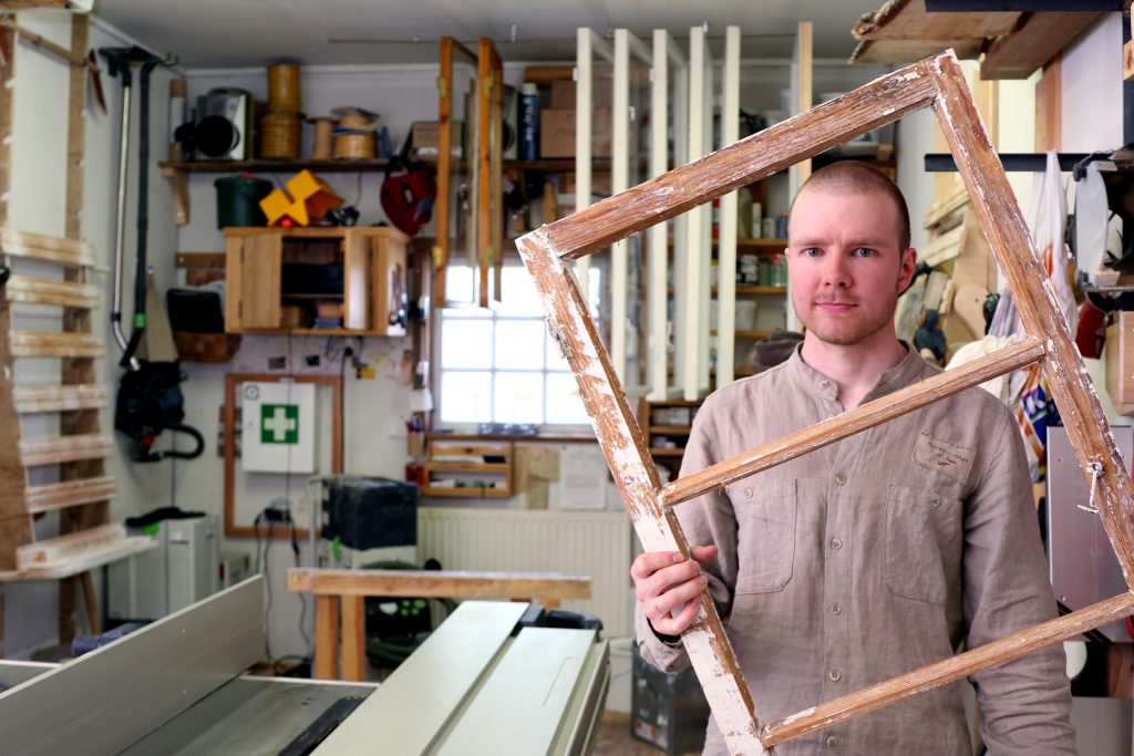 Antti Kolari esittelee töyn alla olevaa ikkunan karmia verstaallaan.